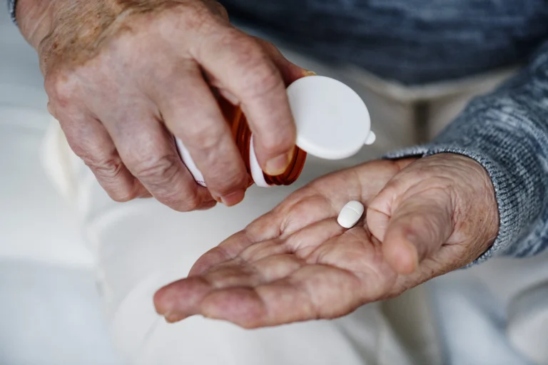 Paciente idoso retirando comprimido de frasco de medicamento — Camzyos (mavacamteno) pelo plano de saúde