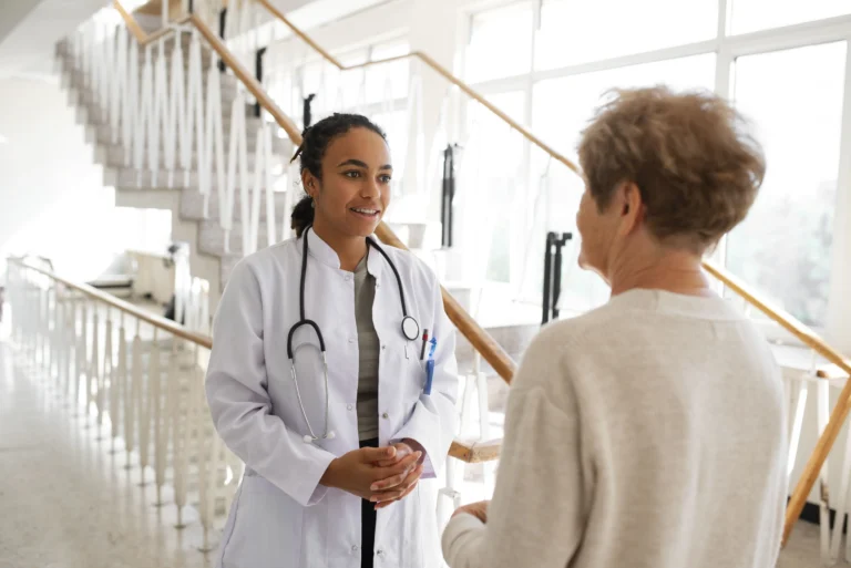 Médica conversando com paciente idosa em corredor de hospital — relação médico-paciente e direitos do paciente